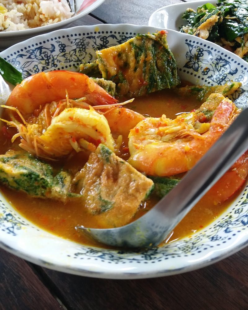 แกงส้มน้ำสีส้มใส่กุ้งและไข่ทอดชะอมในชามลายคราม