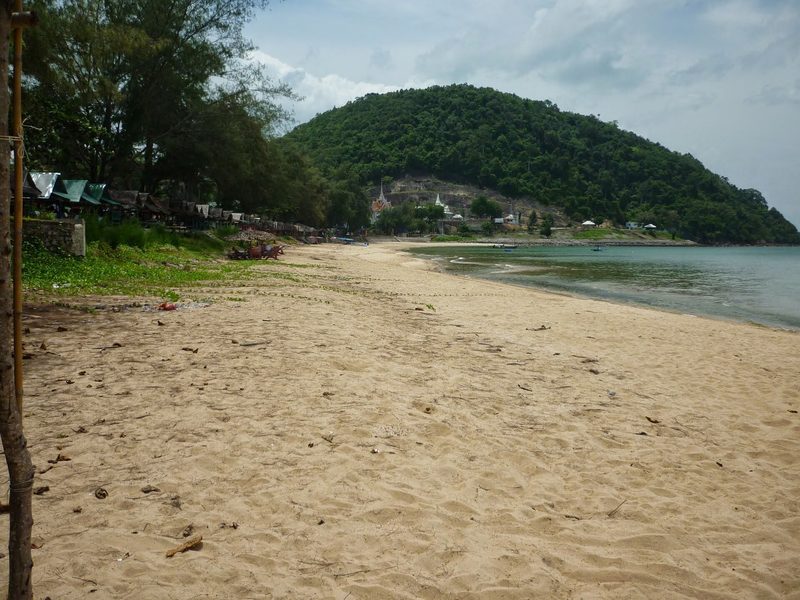 หาดทรายสีอ่อนกับเนินเขาเขียวริมทะเล